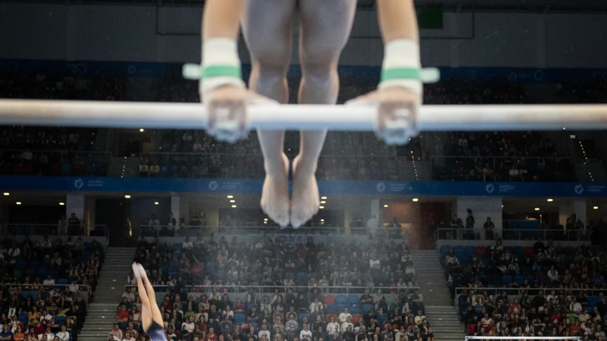Imatge genèrica d'una competició de gimnàstica artística, amb atletes realitzant exercicis en un pavelló.